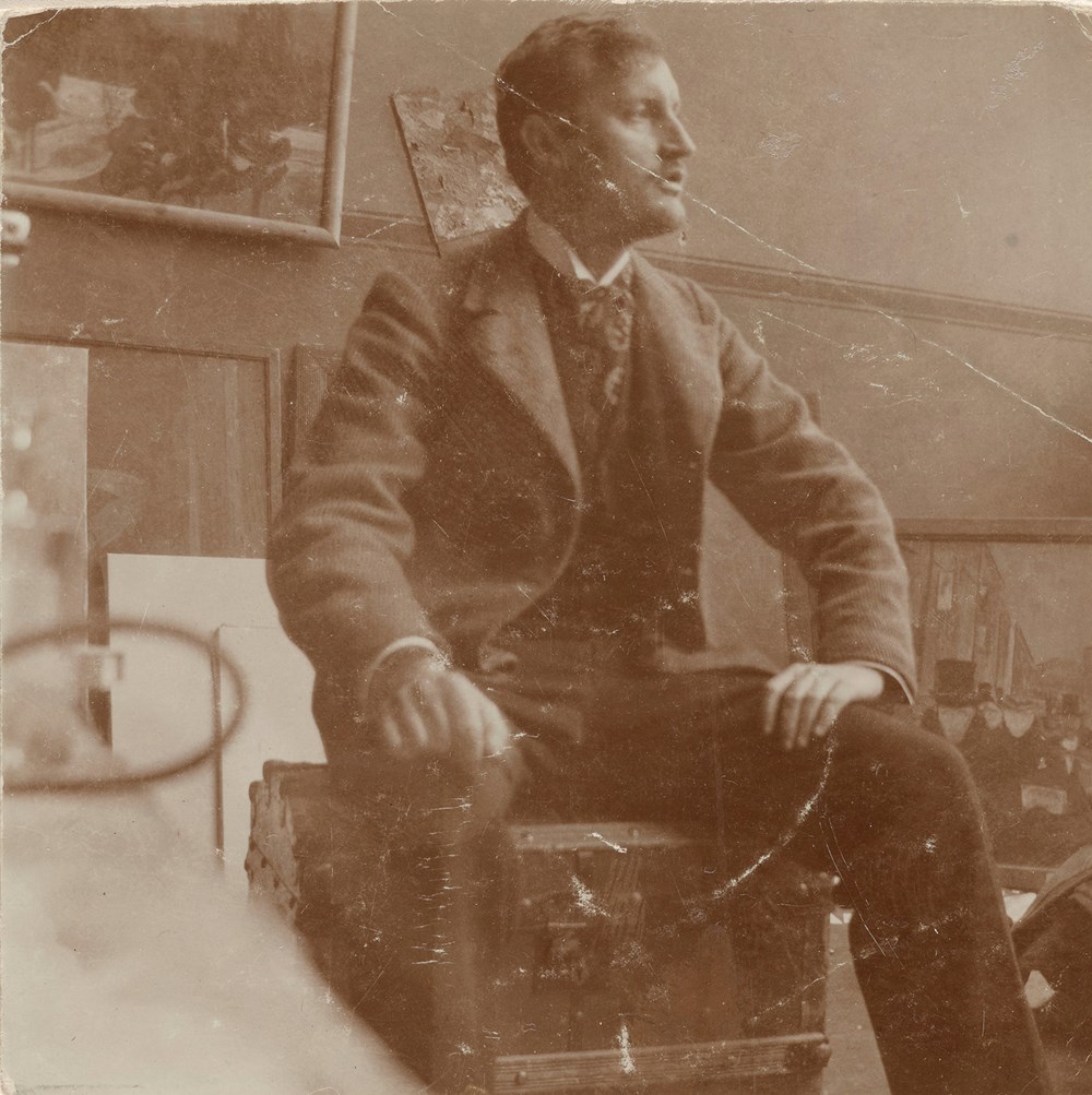 Edvard Munch: Edvard Munch på sin reisekoffert i atelieret i Lützowstrasse 82 I. Fotografi, 1902. Foto © Munchmuseet