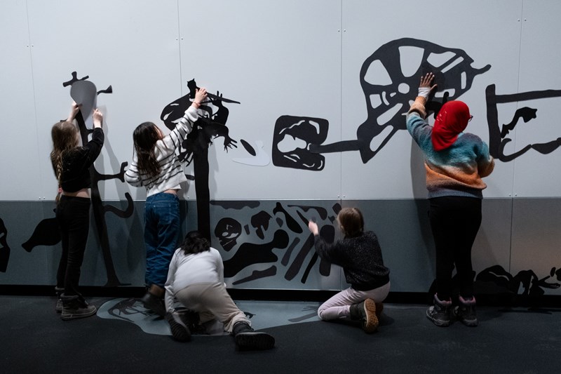 Five children putting magnets on the wall in the exhibition