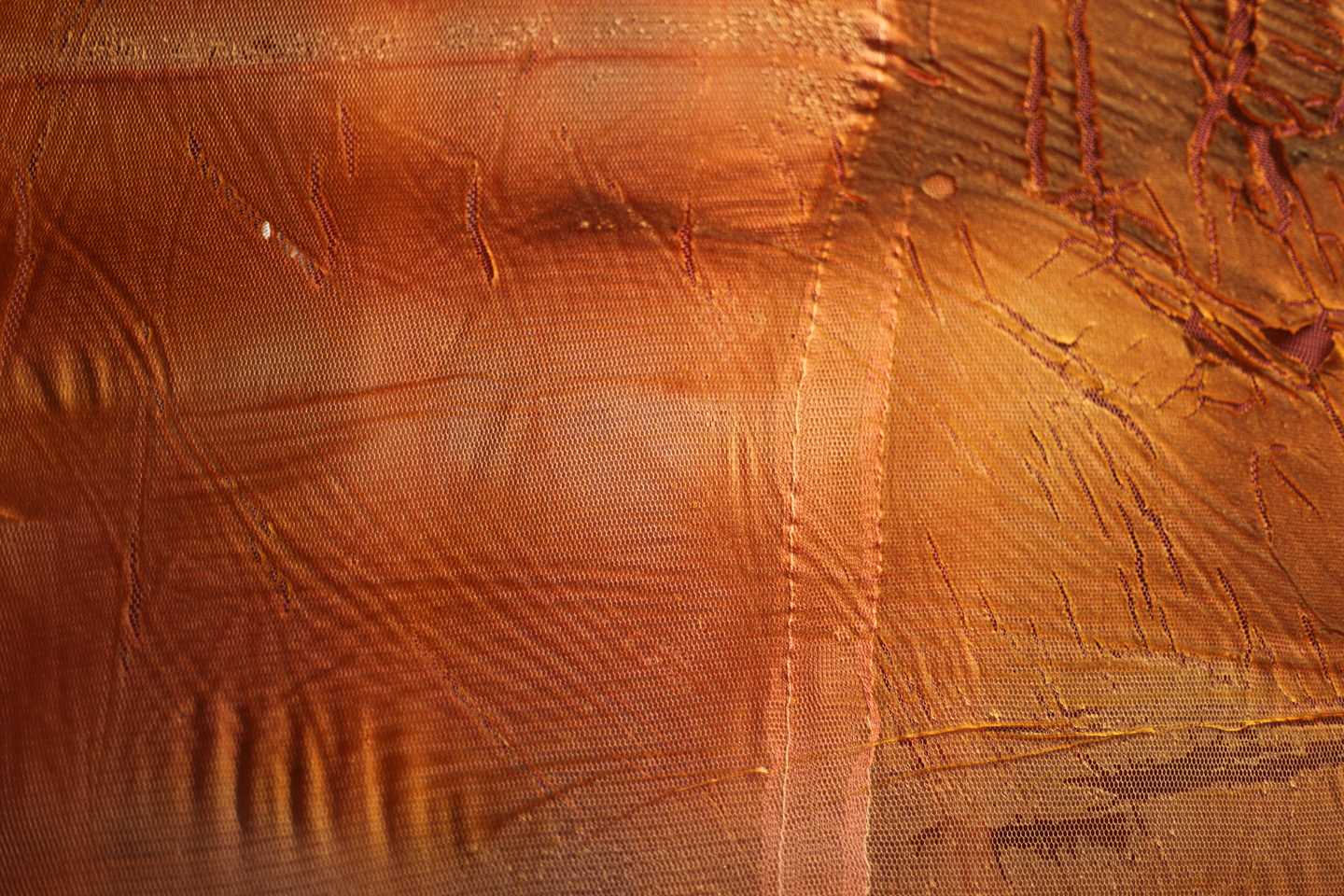 A close-up of a thick, viscous and partially transparent material in warm brown-orange colours.